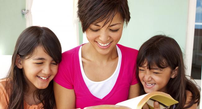 A woman reading with two children.