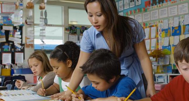 A teacher helping young students with their writing